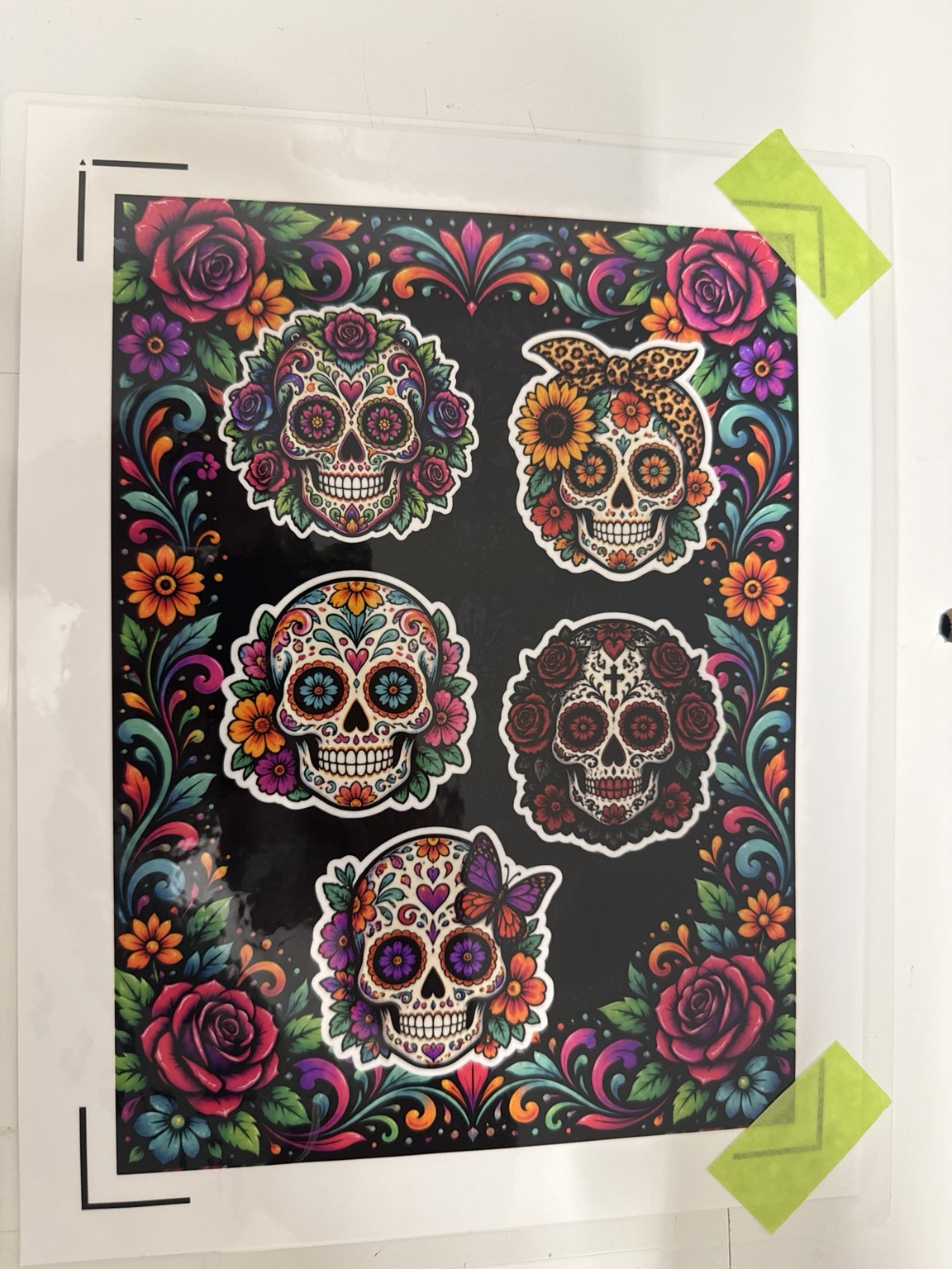 Five colorful sugar skull stickers on a themed floral sticker sheet